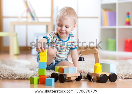 Child boy is happy to play toy building blocks and loader car