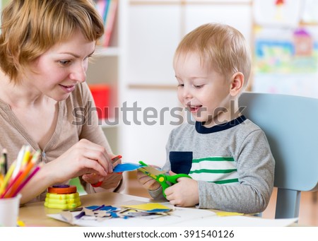 Woman teaches child handcraft at kindergarten or playschool or home