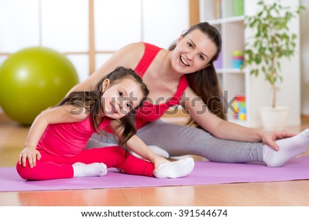Portrait of kid and mother doing physical exercise at home