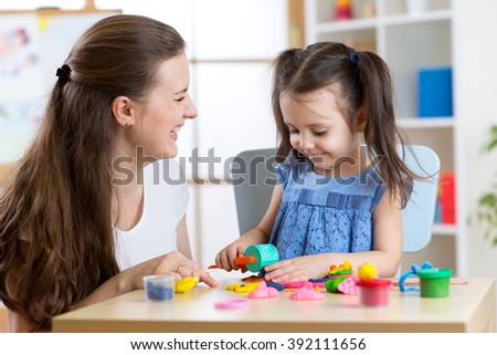 Child girl with her mother sculpts from clay