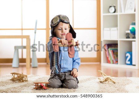 Child boy pretending to be pilot aviator. Kid playing with toy airplanes at home. Travel and dream concept