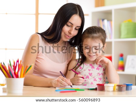 Happy family mother and daughter together paint. Woman helps child girl.