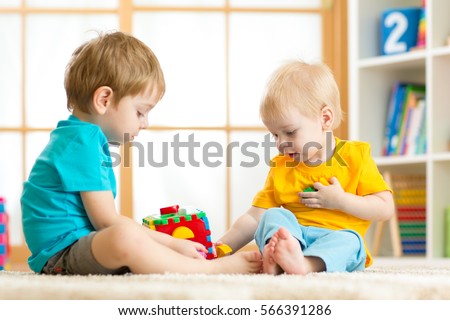 Children toddler and preschooler boys play logical toy learning shapes and colors at home or nursery