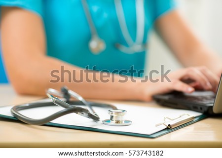 Close-up of stethoscope and clipboard on background of doctor hands with pc