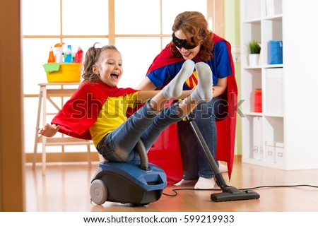Super hero kid flying on vacuum cleaner. Mother and child daughter cleaning the room and have a fun pastime together