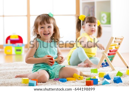 Children toddlers girls play logical toy learning shapes, arithmetic and colors at home, kindergarten or nursery