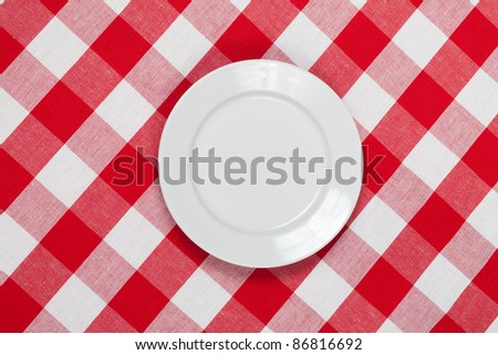 white round plate on red checked tablecloth