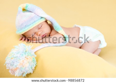 adorable baby with funny cap on her head sleeping on stomach