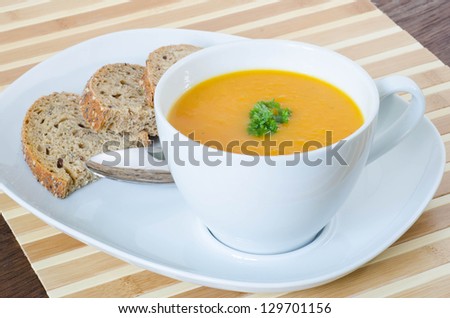 Carrot soup in a cup with bread