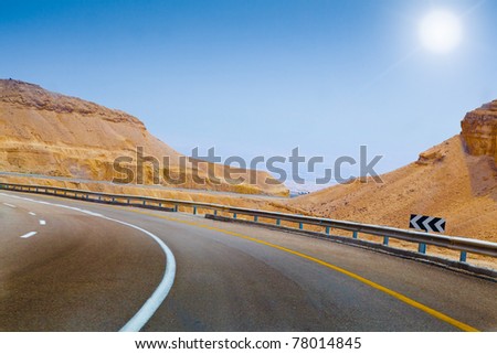 curved sandy road blue sky and sun on the way in Israel