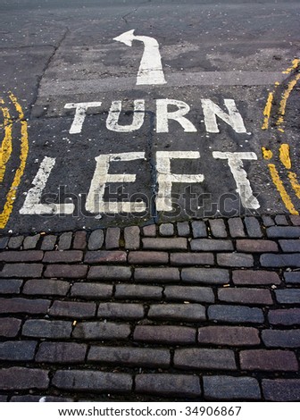 Turn left written in white paint on a road surface