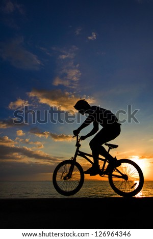 Silhouette of a man on bike jumping in the sunset