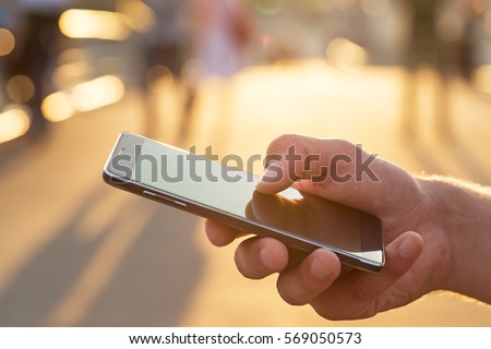 Man using his Mobile Phone outdoor, close up
