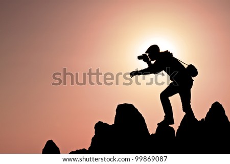 silhouette of a photographer who shoots a sunset on a hill