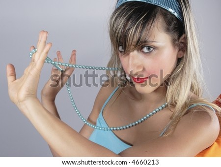 Blond Pin-up style fascinating girl with light blue shirt playing girl with light blue pearl necklace.
