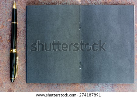 Blank black note with pen on rusty metal plate