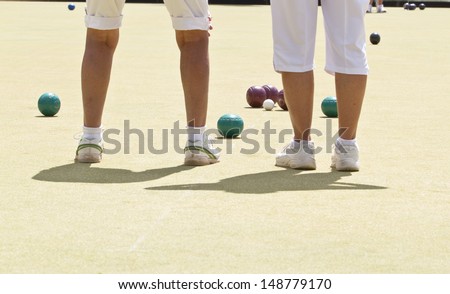 Bowls or lawn bowls is a sport which played on outdoor lawn which is natural grass or artificial turf. Two bowl players on the ground analyzing the ball.