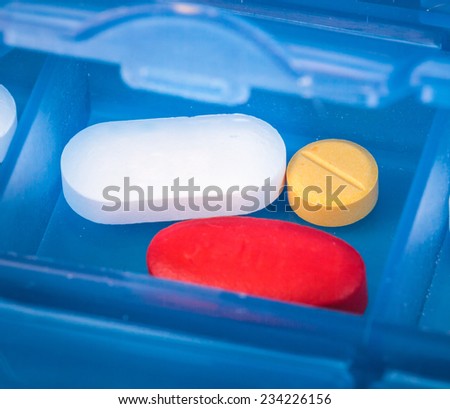 Prescription pills and vitamins in a blue pill box - days of week.