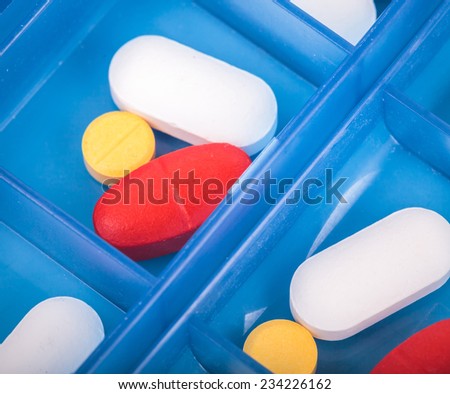 Prescription pills and vitamins in a blue pill box - days of week.