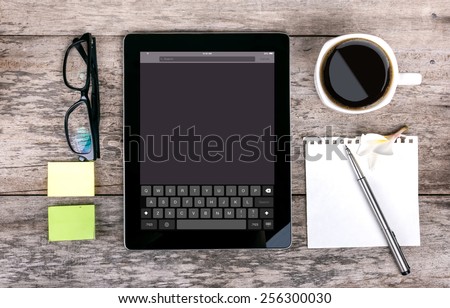tablet as a keyboard glasses pen note paper calculator  with keyboard on screen on wood backgound