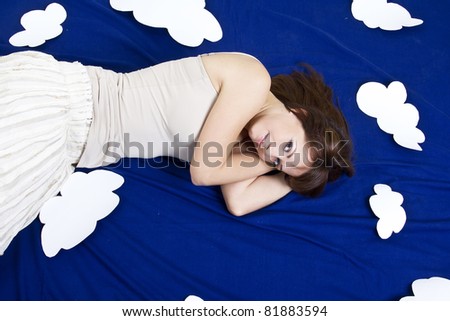 Young girl lying in clouds in studio