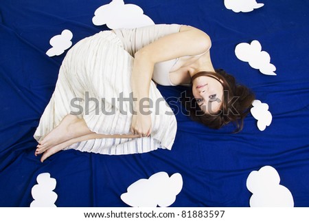 Young beautiful girl lying in the sky with clouds