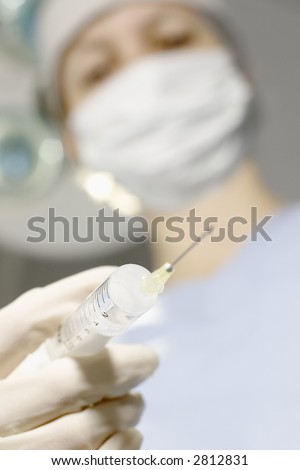 Perspective of a patient on a operating table who sees the doctor above with a syringe in her hand. Focus only on the number 2 on the syringe.