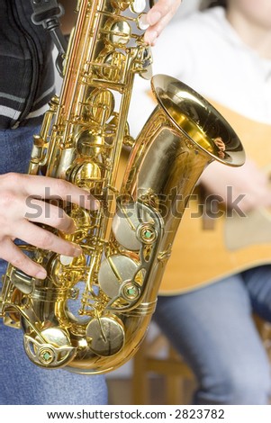 Detail of a music band with saxophone player in the foreground and guitar player in  the background