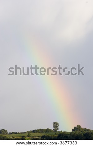 The end of a colorful rainbow below the clouds