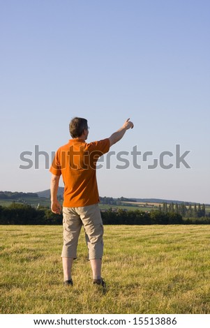 Man pointing with his outstretched arm on a meadow