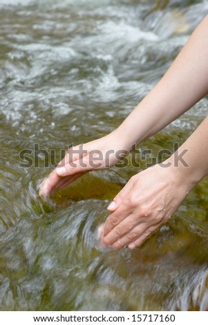 Female hands scooping water from a mountain stream
