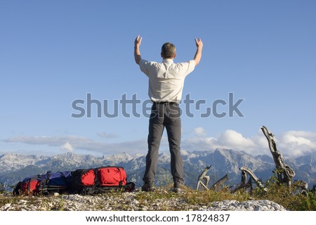 Man with uplifted arms on mountain summit
