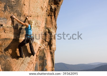 Young woman climbing a rock of sandstone