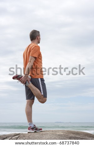 Jogger doing stretching exercises on a beach