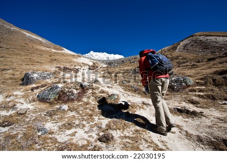 A hiker sets out on a long ascent up a mountain in the border region between Nepal and Tibet