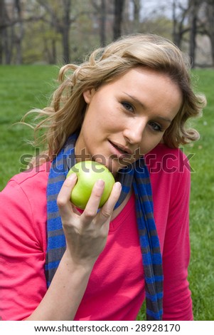 Early 20s female eating an apple in the park