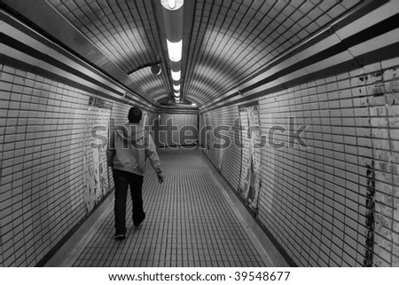 Man walking alone through a tunnel in the London Underground