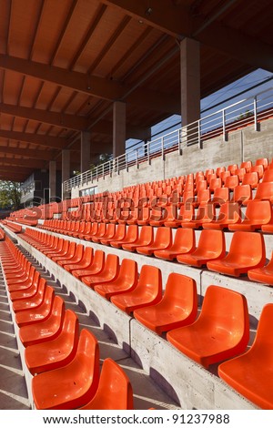 Red plastic seats in a new sunny stadium. Roof made from glue-laminated timber.