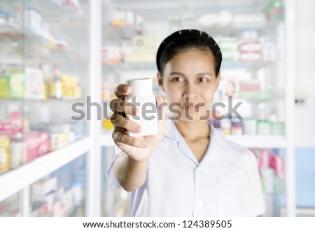 Happy cheerful pharmacist chemist woman standing in pharmacy drugstore with pill bottle