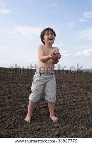 The liitle boy with  black earth in palm