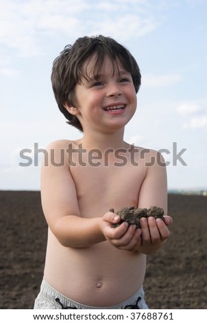 The little boy with  black earth in palm