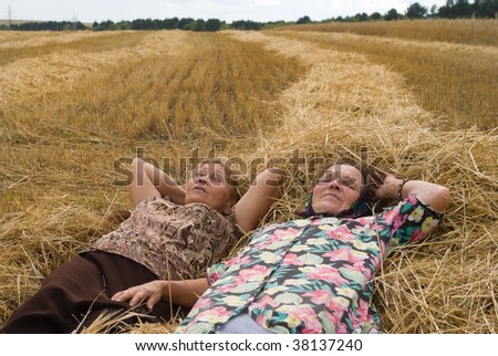 Two old women on field ( lying on hay)