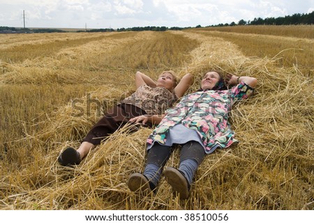 Two old women on field ( lying on hay)