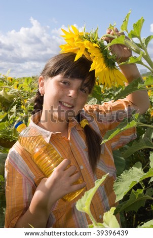 The girl with sunflower and bottle of oil on field