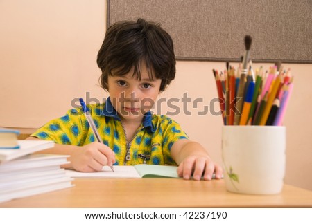 The boy with write-book and pencil in the classroom