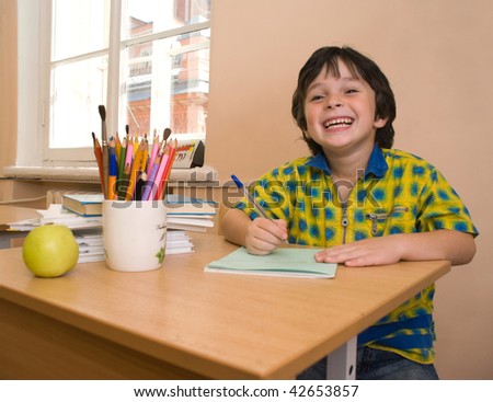 The boy with write-book and green apple and pencil in the classroom