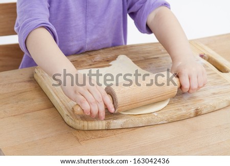 child making fresh pizza beginning with rolling out the dough