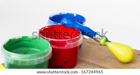 paint in small tubs with paint brush on wooden table