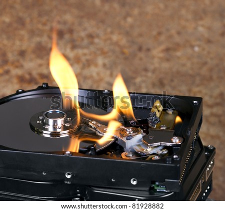 Stack of burning hard drives in close up shot. Nice flames on the drive. Rusty background