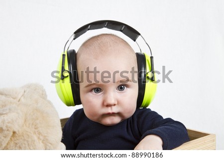 baby with yellow ear protection in loud environment. neutral grey background